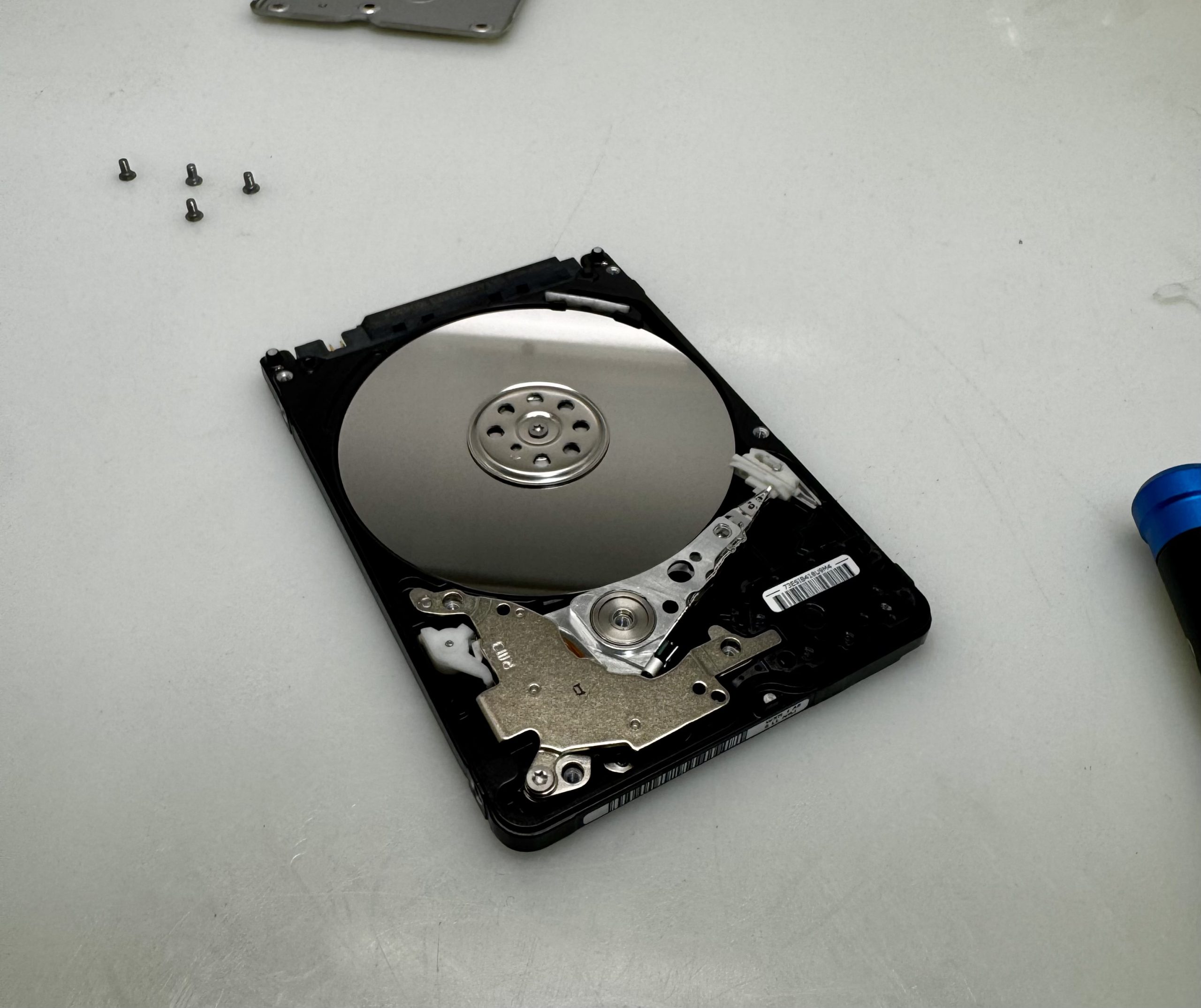 An opened laptop hard drive with the platter exposed on a Gadget Repair Pro workbench