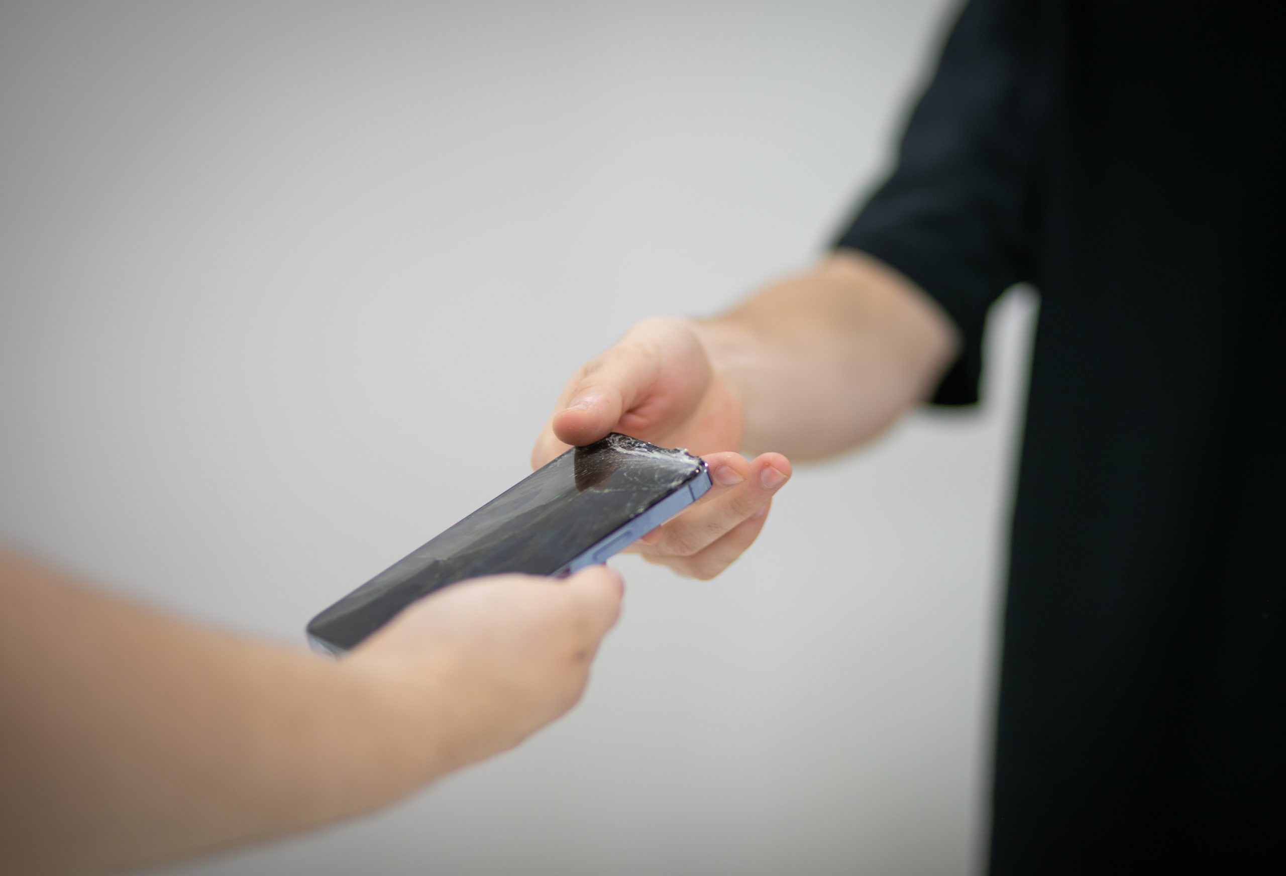 A customer handing over their phone at the Gadget Repair Pro counter in Ithaca.